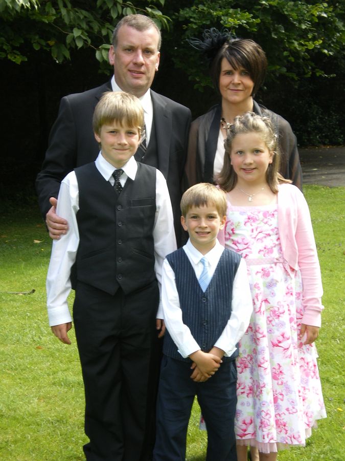 The family together in the garden in the early years — John with his parents, his sister Elizabeth and his brother Robert